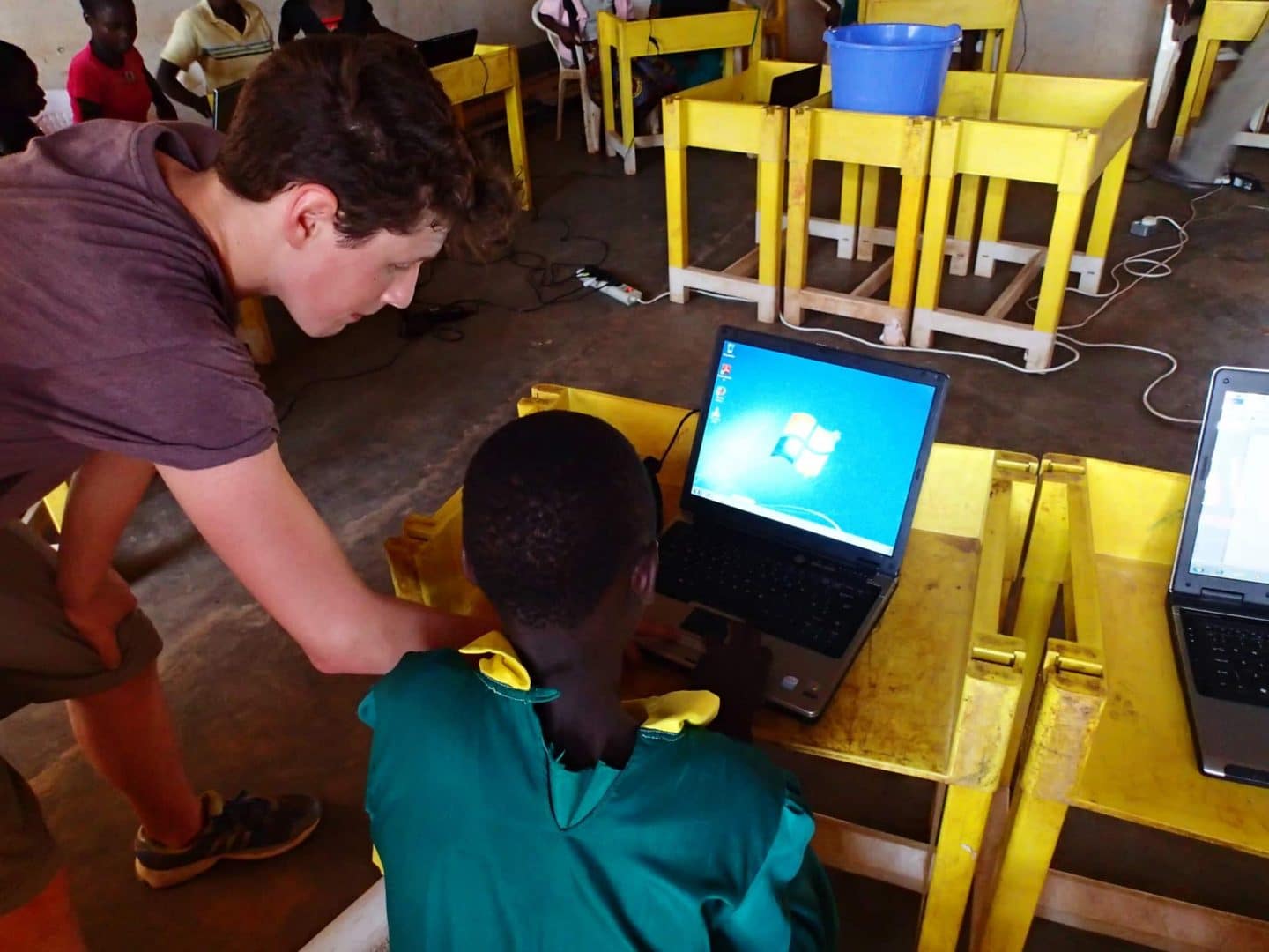 A young person learning computer skills with a visitor