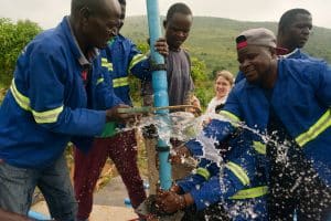 group of people repairing a water pump with water splashing out
